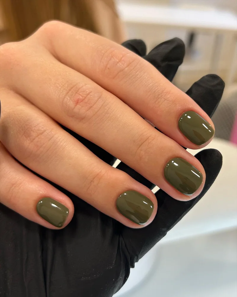 Короткие оливковые ногти, рядом черная перчатка