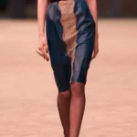 Модель в юбке до колена из панелей кожи двух цветов на показе Saint Laurent осень-зима 2026